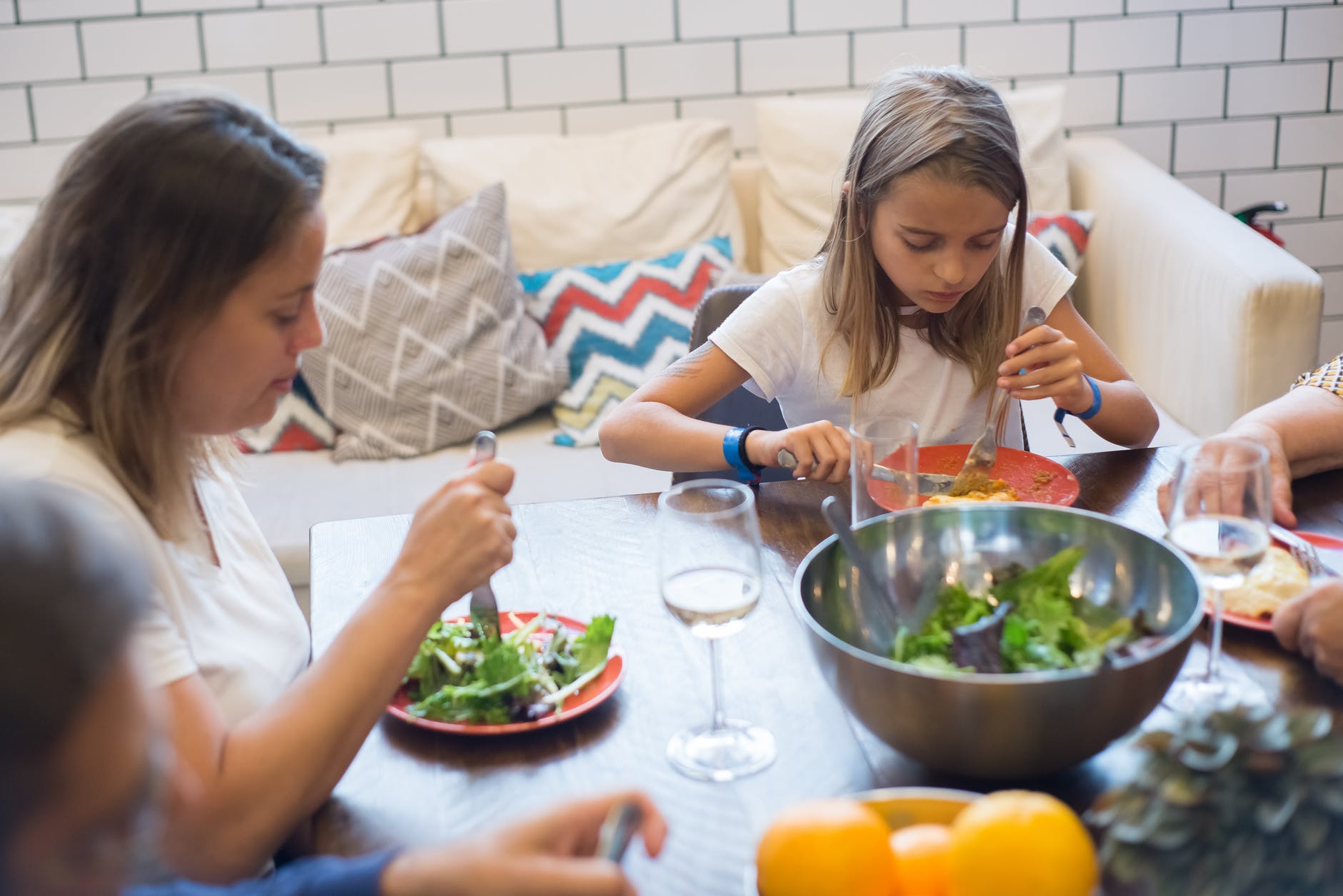 girl and woman in white shirt eating vegetable salad