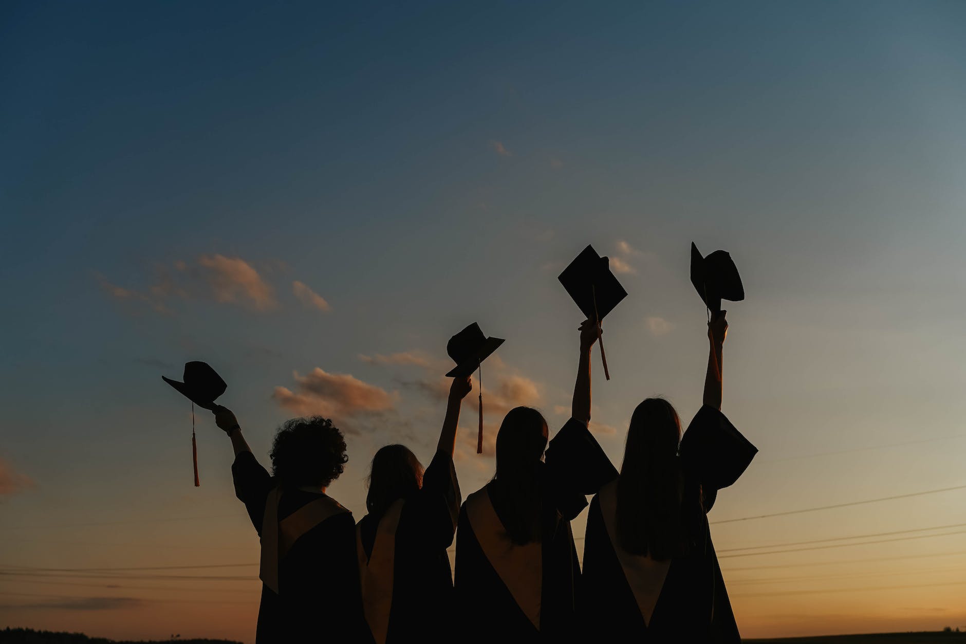 silhouette of people raising their graduation hats