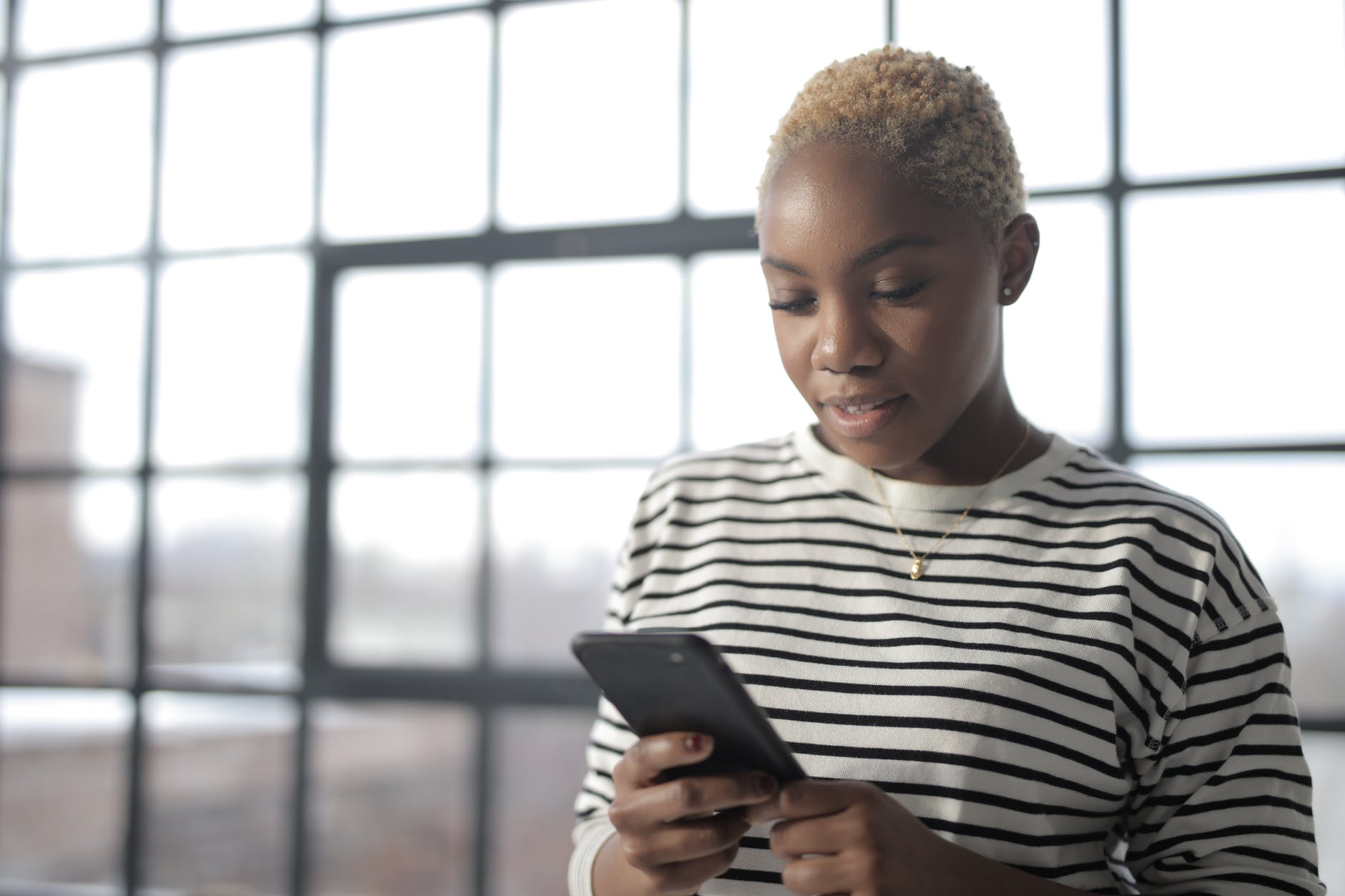 woman in white and black striped crew neck shirt holding black smartphone